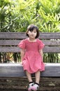 Asian child girl is smiling happily, while sitting in the garden. Royalty Free Stock Photo