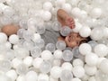 Asian child girl is smiling while lying in white balls at the playground. Royalty Free Stock Photo