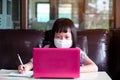 Asian child girl studying homework and wearing face mask during her online lesson at home for protect virus Royalty Free Stock Photo