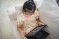 Asian child girl using pen and touch drawing on tablet display screen. Baby smiling funny time to use tablet. Too much screen time Royalty Free Stock Photo