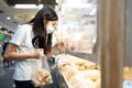 Asian child girl wear face mask,buying bread in bakery have a plastic shield partition between customers at shopping mall during