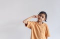 Asian child girl wear orange T-shirt pointing to head gesture thinking. Thing ideas concept. Royalty Free Stock Photo