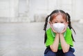 Asian child girl wearing a protection mask while outside to against PM 2.5 air pollution with pointing up in Bangkok city.