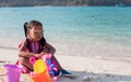Asian child girl wearing sunglasses having fun to play with sand on beach in summer vacation Royalty Free Stock Photo
