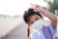 Asian child girl wearing white face mask when going to school, protecting against dust, toxic smoke, air pollution, bright smiling Royalty Free Stock Photo