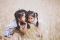 Asian child girls hugging their mother and having fun to play with mother in the barley field in vintage color tone Royalty Free Stock Photo