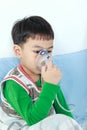 Asian child holds a mask vapor inhaler for treatment of asthma.