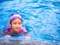Asian child or kid girl wearing swimming suit to learning on swimming pool , learn and training swim on kick board Royalty Free Stock Photo