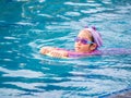 Asian child or kid girl wearing swimming suit to learning on swimming pool , learn and training swim on kick board Royalty Free Stock Photo