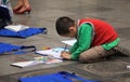 Asian child learning to draw on the ground at a park near Hoan Kiem lake in Hanoi