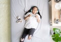 Asian child little girl play smartphone with wearing headphones on the bed Royalty Free Stock Photo