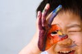 Asian child painted hand and showing fingers sign ok on his face. Close up. copy space