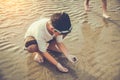 Asian child has fun digging in the sand. Young boy enjoying on b