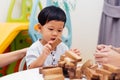 Asian child playing with wooden blocks in the room at home. A kind of educational toys for preschool and kindergarten kids Royalty Free Stock Photo