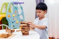 Asian child playing with wooden blocks in the room at home. A kind of educational toys for preschool and kindergarten kids. Royalty Free Stock Photo