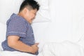 Asian child suffering from stomachache and lying on bed top view s Royalty Free Stock Photo