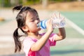 Asian child are thirsty. Kid are tired from playing in hot weather. Children drink some water from plastic bottles.