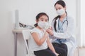 Asian child wearing face mask getting vaccinated during coronavirus or covid-19 pandemic at hospital,Vaccination concept