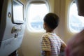 Asian children look at the aerial view of the sky and clouds outside the plane window while sitting on the plane seat Royalty Free Stock Photo