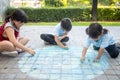 Asian children play outdoors. Child girl draws a planet globe with a map of the world colored chalk on the pavement, asphalt.