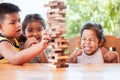 Asian children playing wood blocks stack game together with fun