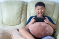 Asian Children sit on sofa are serious about playing games on mobile phone Royalty Free Stock Photo