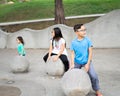 Asian children sitting on the concrete sphere ball shape in the park