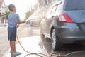 Asian children are using water hose to washing car