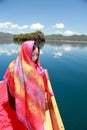 Asian Chinese beauty in red dress with red scraf on head, at Yunnan Lugu lake, enjoy free time