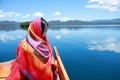 Asian Chinese beauty in red dress with red scraf on head, at Yunnan Lugu lake, enjoy free time