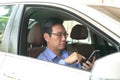 Businessman messaging on his cell phone inside his car