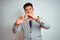 Asian chinese businessman wearing suit and tie standing over isolated yellow background smiling in love doing heart symbol shape Royalty Free Stock Photo