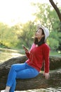 Asian Chinese careless girl is listening to music sit on a tree by a river in spring autumn park Royalty Free Stock Photo