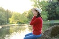 Asian Chinese careless girl is listening to music sit on a tree by a river in spring autumn park Royalty Free Stock Photo