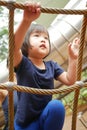 Asian Chinese Child climbing rope obstacle course watched by adult