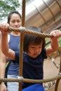 Asian Chinese Child climbing rope obstacle course watched by adult
