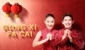 Asian Chinese couple in cheongsam dress with congratulations gesture and Gong Xi Fa Cai text and Chinese lanterns Royalty Free Stock Photo