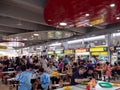 Asian Chinese diners having a meal and socialising at a crowded hawker centre in Singapore, Southeast Asia while others queue to Royalty Free Stock Photo