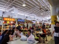 Asian Chinese diners having a meal and socialising at a crowded hawker centre in Singapore, Southeast Asia while others queue to Royalty Free Stock Photo