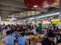 Asian Chinese diners having a meal and socialising at a crowded hawker centre in Singapore, Southeast Asia while others queue to