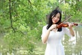 Asian Eastern Chinese young artist woman play violin by river in a park garden outdoor nature sunset sunrise day musical art Royalty Free Stock Photo