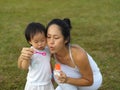 Asian chinese female parent blowing bubbles with baby girl