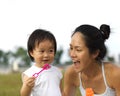 Asian chinese female parent blowing bubbles with baby girl