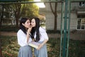 Two lovely Asian Chinese pretty girls wear student suit in school best friends smile laugh share snack cookie in nature Royalty Free Stock Photo