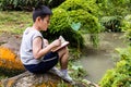 Asian Chinese little boy reading book in the park Royalty Free Stock Photo