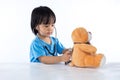 Asian Chinese little doctor girl examine teddy bear Royalty Free Stock Photo