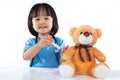 Asian Chinese little doctor girl giving injection to teddy bear Royalty Free Stock Photo