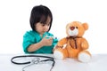 Asian Chinese little doctor girl giving injection to teddy bear Royalty Free Stock Photo