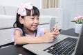 Asian Chinese little girl busy reading mobile phone and laptop