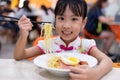 Asian Chinese little girl eating noodles with chopsticks Royalty Free Stock Photo